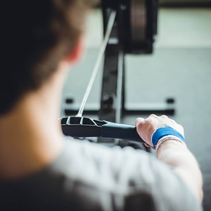 Homme qui fait du rameur pour son programme cardio salle de sport